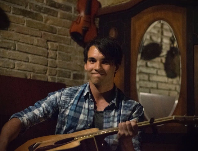 A picture of Maxim playing the guitar in a live performance